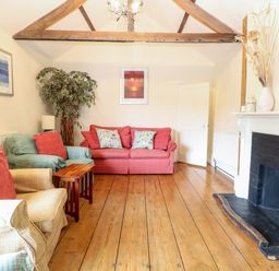 A living room with sofas wooden floor and a fireplace at Forge House in Cley Next The Sea