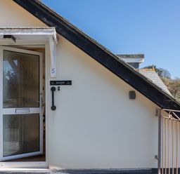 The entrance door of a house with the number 5 and name Goody on the wall at Goody in Hope Cove