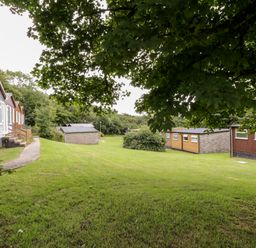 A grassy area with several small buildings and trees at 8 The Park in Kilkhampton