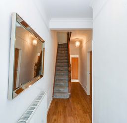 A hallway with a staircase and mirror at Y Berth in Caernarfon