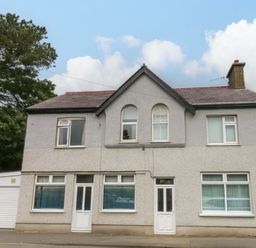 A house with a garage and trees in front at Y Berth in Llanberis