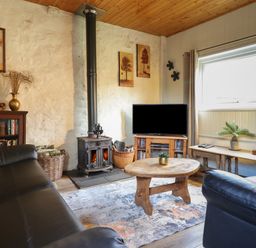 A living room with a wood stove television and wooden furniture at Tyn Y Cefn Near Blaenau Ffestiniog