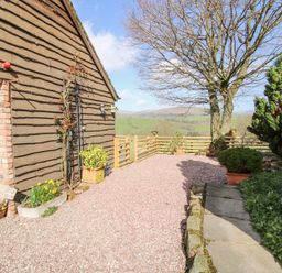 An outdoor area with a gravel path wooden fencing trees and plants at The Retreat in Pedairffordd near Llanrhaeadr-Ym-Mochnant