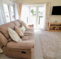 A living room with a brown sofa and cushions a rug a wall-mounted TV and a wooden TV stand at Number 15 in Carnforth