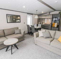 A living room with two sofas a small round table and a dining table with chairs in a kitchen area at Finch 59 in Cayton