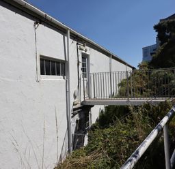 An exterior view of a white building with a metal balcony and railings surrounded by greenery at Starfish in Sennen Cove