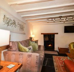 A living room with a sofa and a fireplace at Woodview in Looe