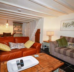 A living room with a brown sofa, coffee table, and lamp at Woodview in Looe