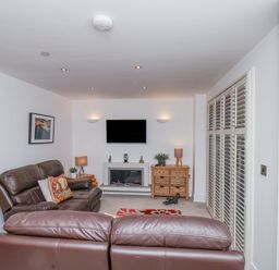 A living room with brown leather sofas a wall-mounted television and a fireplace at Above & Beyond in Whitby
