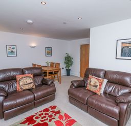 A living room with two brown leather sofas and a dining table at Above & Beyond in Whitby