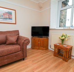 A living room with a sofa and television at Maypole Cottage in Fylingthorpe