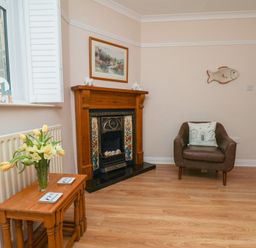 A living room with a fireplace and a chair at Maypole Cottage in Fylingthorpe