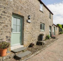 An outdoor area with a green door and stone wall at Swallows Retreat in Tenby