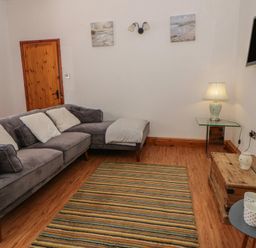 A living room with a sofa and a table at Swallows Retreat in Tenby