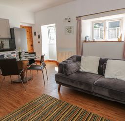 A living room with a sofa and dining table at Swallows Retreat in Tenby