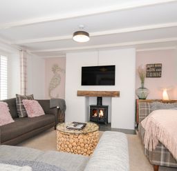 A living room with patterned and plain sofas a wood-burning stove and a round coffee table at Quay House in Charlestown