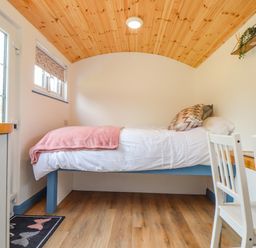 A small bedroom with a single bed wooden ceiling and a desk with two chairs at Rose in Illogan