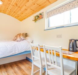 A bedroom with a single bed white chairs and a wooden desk with an electric kettle at Rose Illogan