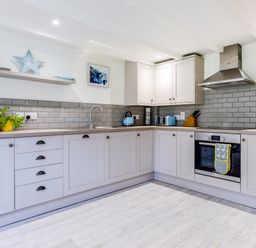 A kitchen with cabinets a stove a microwave and kitchen utensils at Goose Cottage within the Helland Barton Farm collection Delabole