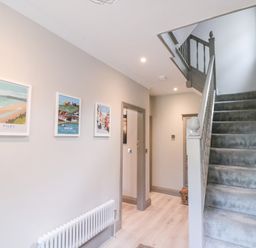 A hallway with carpeted stairs and framed pictures on the wall at 41 Chatsworth Gardens in Scarborough