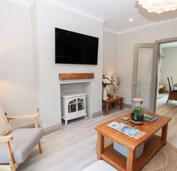 A living room with a wall-mounted television a wooden coffee table and a gray armchair at 41 Chatsworth Gardens Scarborough