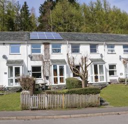 A row of white terraced houses with solar panels on the roof and a small fenced garden in front at Fellside View in Chapel Stile