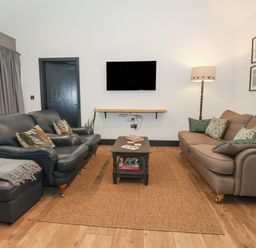 A living room with two sofas a coffee table a floor lamp and a wall-mounted television at Skylark in Bishop Wilton