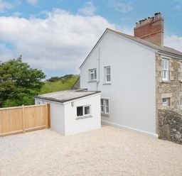 Exterior of a semi detached stone and white house with gravel driveway and wooden gate at Carvannel Cottages North Cliffs near Portreath