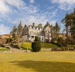 A large stone house with multiple windows surrounded by trees and a grassy lawn at Heatherbrae in Middleton-In-Teesdale