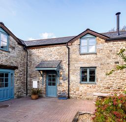 Exterior view of a stone house with blue framed windows and doors and plants in front at Trelawney in Mawnan Smith Near Falmouth