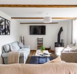 A living room with sofas a coffee table a wall-mounted TV and a wood-burning stove at Trelawney Mawnan Smith Near Falmouth