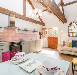 A kitchen and living area with wooden beams and a small sofa at The Forge in Taunton