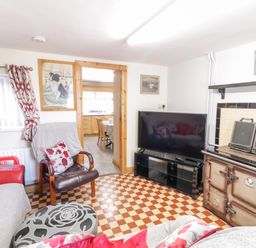 A living room with a checkered floor a TV a vintage stove and seating at Peters Farmhouse in Cookstown