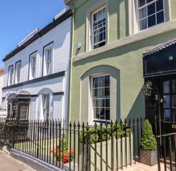 A row of townhouses with black wrought iron fences and green plants by the doors at Drake's Retreat in Plymouth