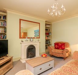 A living room with a fireplace armchair sofa coffee table and TV at Drake's Retreat in Plymouth