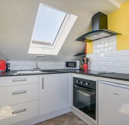 A kitchen with a skylight window a sink an oven a microwave and a small refrigerator at Ayla Lyme Regis