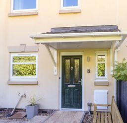A house entrance with a green front door a covered porch two windows a wooden bench and a potted plant at 3 Trem Y Dolydd in Dolgarrog near Llanrwst