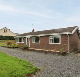 A single-story brick house with a gravel driveway and a green garage at Llwynon in Goginan near Aberystwyth