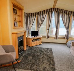 A living room with a fireplace a rocking chair a TV on a wooden cabinet a sofa and striped curtains at Rosehaven in Tegryn near Crymych