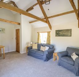 A living room with wooden beams two blue sofas and a small dining table at The Parlour in Llangoedmor near Cardigan