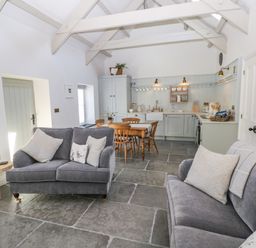 A kitchen and living area with grey sofas wooden dining table and chairs at Catamouse in Milford Haven