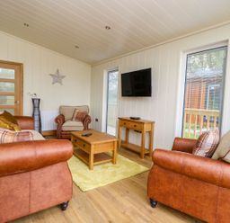 A sitting room with leather sofas a wooden coffee table a wooden side table and a wall mounted television at Robin Lodge in Gargrave