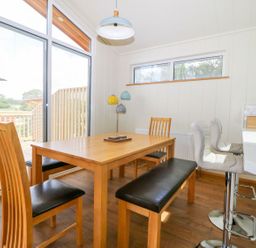 A dining area with wooden table chairs bench and bar stools near large window at Robin Lodge in Gargrave
