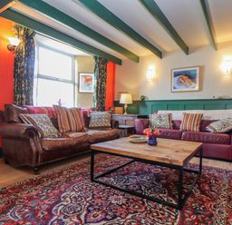 A living room with two leather sofas a wooden coffee table and a patterned rug at Trewenna Roseland Tregony
