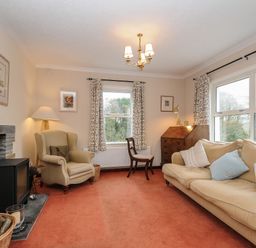 A living room with an armchair sofa wooden chair wooden cabinet and a fireplace at Kirland in St Kew Highway