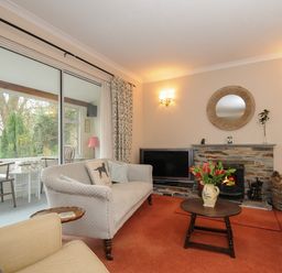 A living room with sofas a coffee table with flowers a fireplace and a television at Kirland in St Kew Highway