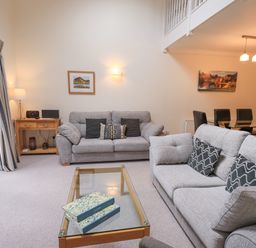 A living room with two grey sofas and a glass coffee table with books at Beechside in Ambleside