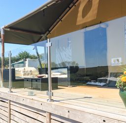 An outdoor deck with seating area and glass railing at Semira Tent Lodge in Blackawton
