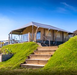 A tent lodge with wooden stairs and a grassy mound at Semira Tent Lodge in Blackawton