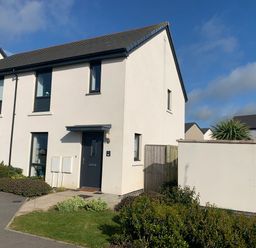 The exterior of a two-story end terrace house with a dark front door and several windows in a residential area at 2 Boathouse Terrace in Mawgan Porth